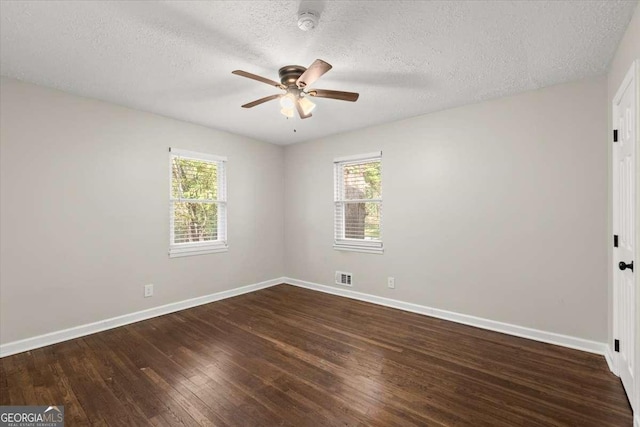 empty room with ceiling fan, dark hardwood / wood-style flooring, and a textured ceiling