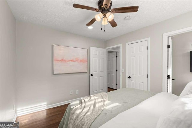 bedroom featuring a textured ceiling, dark hardwood / wood-style floors, and ceiling fan