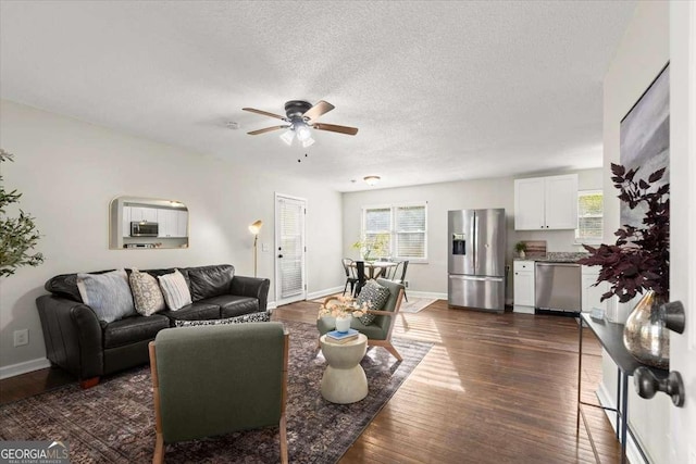 living room with a textured ceiling, ceiling fan, and dark wood-type flooring