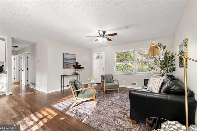 living room featuring ceiling fan, wood-type flooring, and a textured ceiling