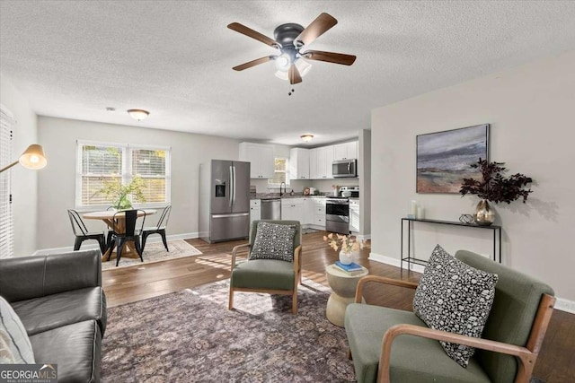 living room with ceiling fan, sink, a textured ceiling, and hardwood / wood-style flooring