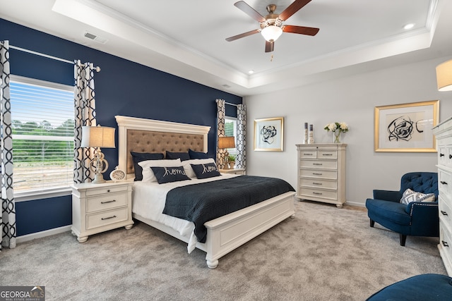 carpeted bedroom with a tray ceiling, ceiling fan, and crown molding