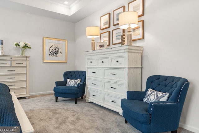 sitting room with light colored carpet, a raised ceiling, and crown molding