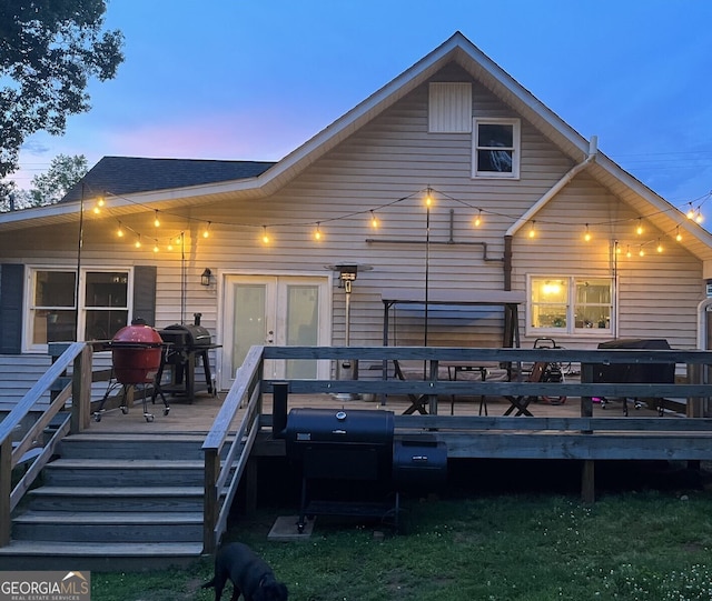 back house at dusk with french doors and a deck