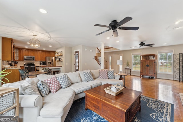 living room with hardwood / wood-style floors and ceiling fan with notable chandelier