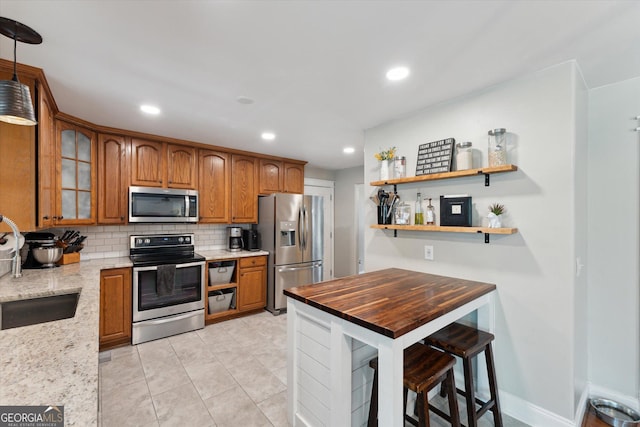 kitchen featuring light stone countertops, appliances with stainless steel finishes, backsplash, sink, and light tile patterned floors