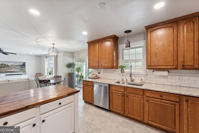 kitchen featuring pendant lighting, dishwasher, sink, a wealth of natural light, and butcher block countertops