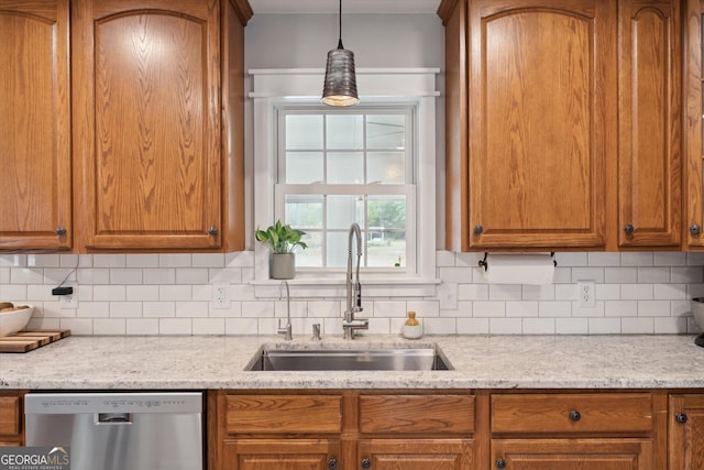 kitchen featuring light stone countertops, sink, tasteful backsplash, stainless steel dishwasher, and pendant lighting