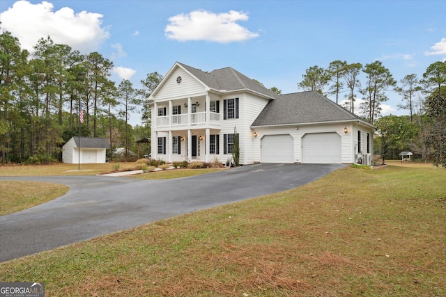 view of front of house with a balcony, a front lawn, a garage, covered porch, and a shed