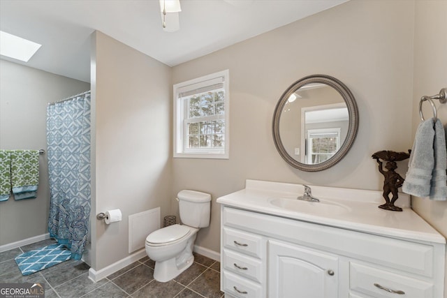 bathroom featuring tile patterned flooring, vanity, toilet, and a skylight