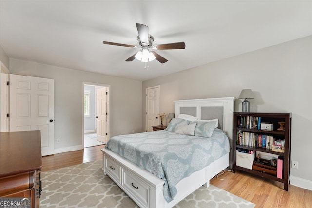 bedroom featuring ceiling fan, ensuite bathroom, and light wood-type flooring