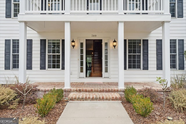 doorway to property with covered porch and a balcony