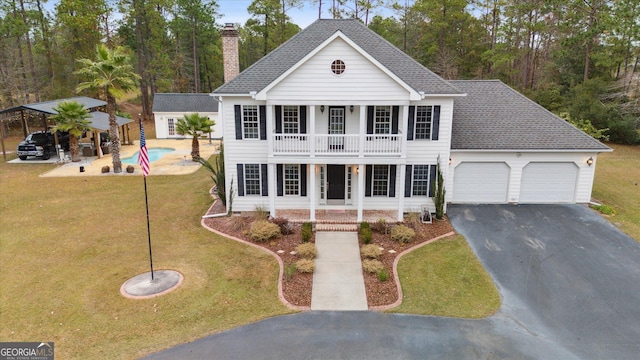 view of front facade featuring a garage, a balcony, a front lawn, covered porch, and a carport