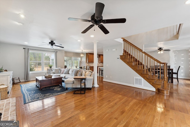 living room with ornate columns, ceiling fan, and light wood-type flooring