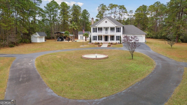 view of front facade featuring a balcony, a front yard, and a storage unit