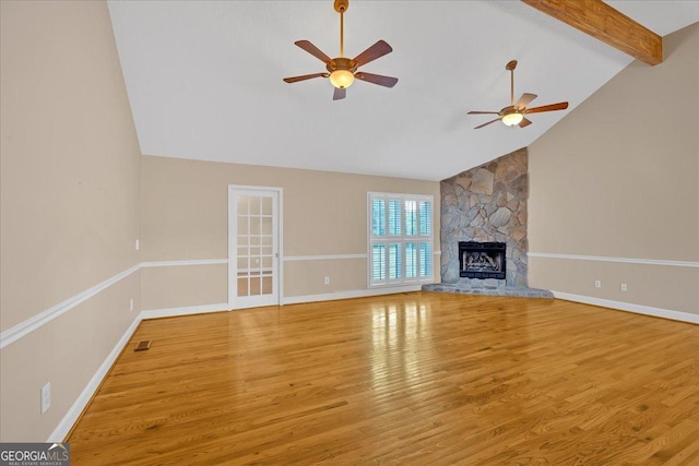 unfurnished living room featuring light wood-type flooring, ceiling fan, beam ceiling, high vaulted ceiling, and a stone fireplace