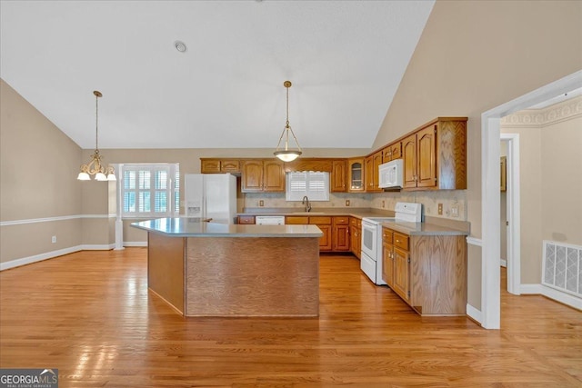 kitchen featuring a kitchen island, light wood-type flooring, white appliances, and high vaulted ceiling