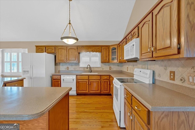 kitchen featuring light wood-type flooring, white appliances, vaulted ceiling, sink, and pendant lighting