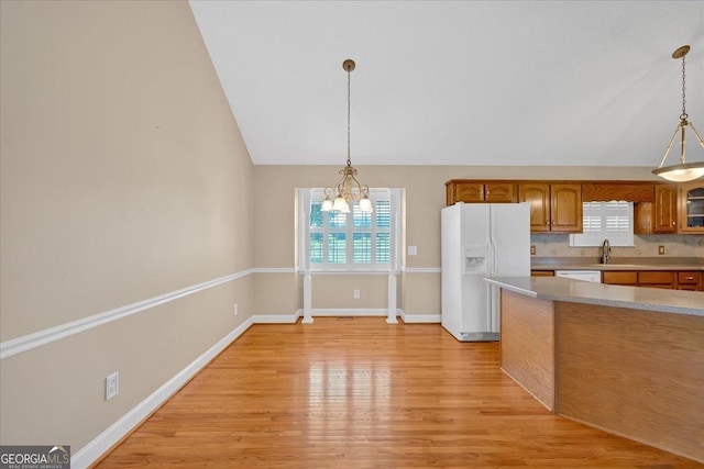 kitchen with a chandelier, white appliances, light hardwood / wood-style floors, and hanging light fixtures