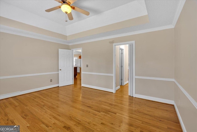 empty room with ceiling fan, light hardwood / wood-style floors, a textured ceiling, and ornamental molding