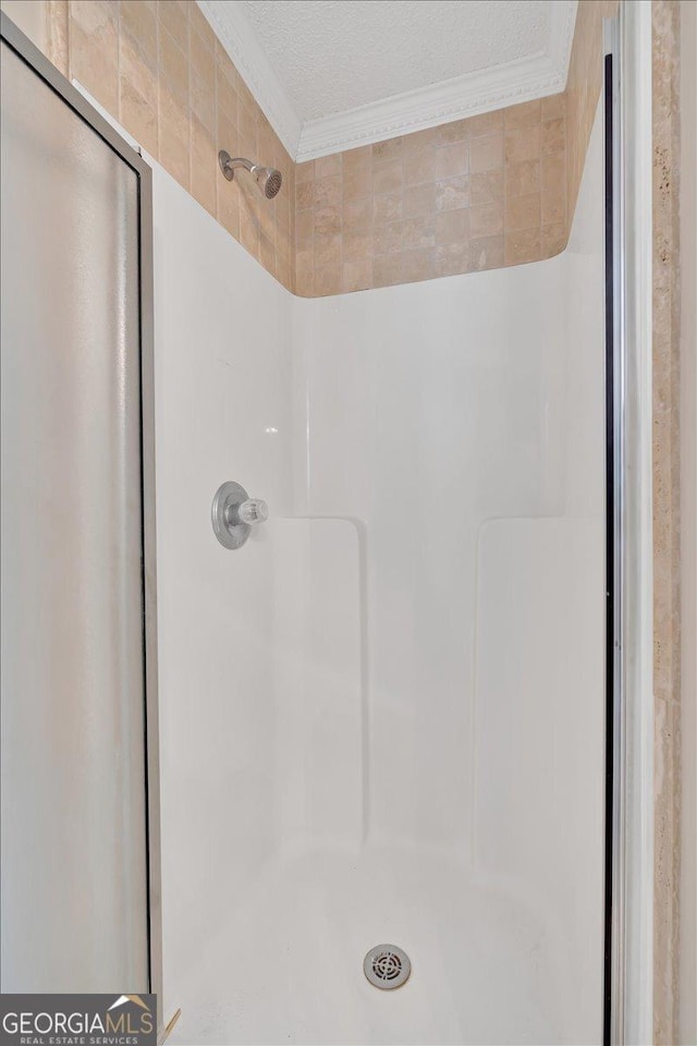 bathroom with crown molding, a textured ceiling, and walk in shower