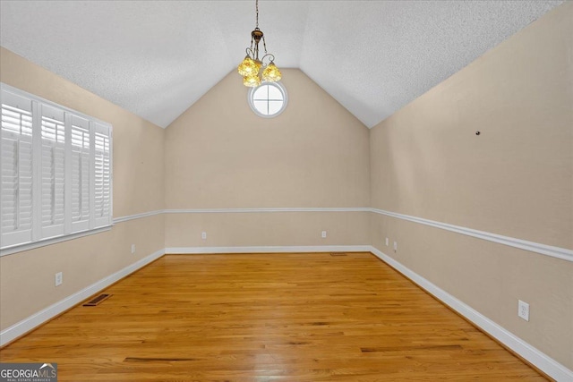 unfurnished room with a wealth of natural light, wood-type flooring, and a textured ceiling