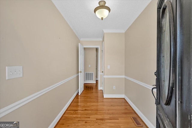 entrance foyer featuring a textured ceiling, light hardwood / wood-style flooring, and ornamental molding