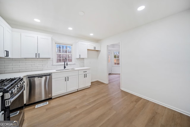 kitchen featuring white cabinetry, sink, stainless steel appliances, and light hardwood / wood-style flooring