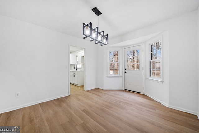 interior space with sink, a notable chandelier, and light wood-type flooring