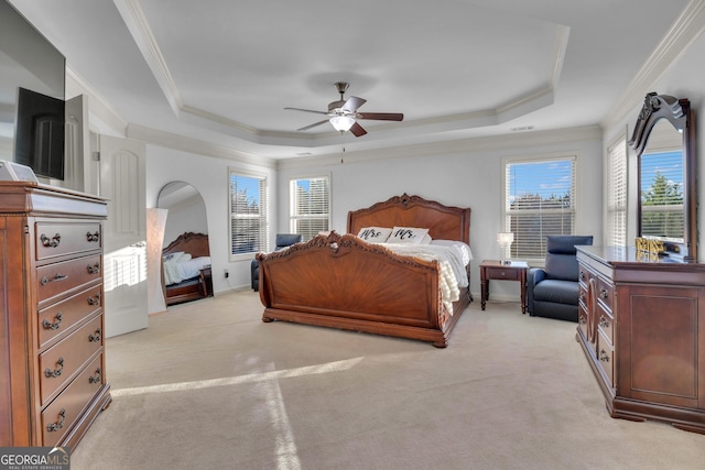 carpeted bedroom with ceiling fan, a raised ceiling, ornamental molding, and multiple windows