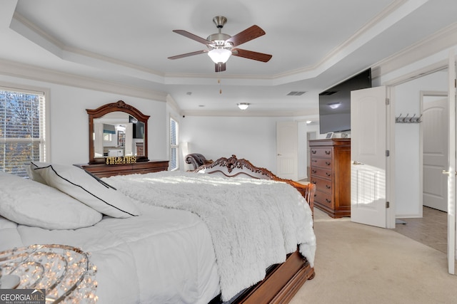 bedroom featuring ceiling fan, a raised ceiling, light colored carpet, and ornamental molding