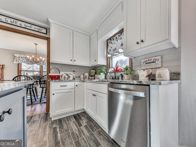 kitchen featuring dishwasher, white cabinets, sink, a wealth of natural light, and a notable chandelier