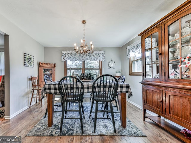 dining space with a wealth of natural light, light hardwood / wood-style floors, and a notable chandelier