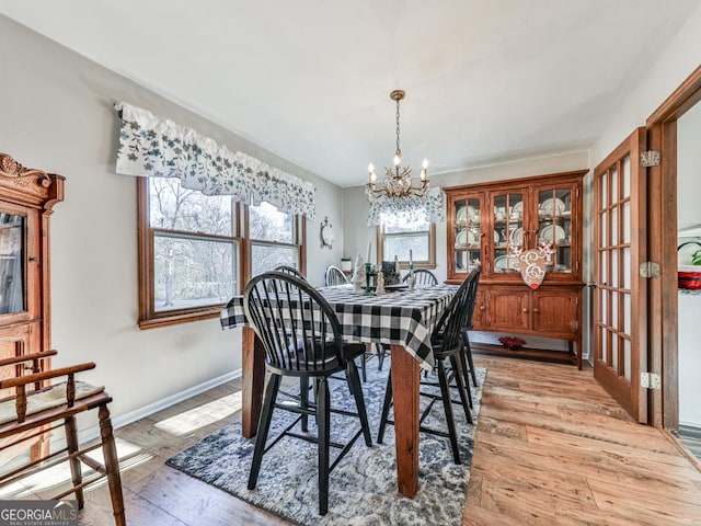 dining space with light hardwood / wood-style flooring and an inviting chandelier