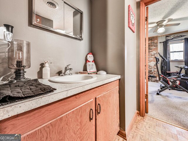 bathroom featuring a textured ceiling, vanity, parquet floors, and ceiling fan