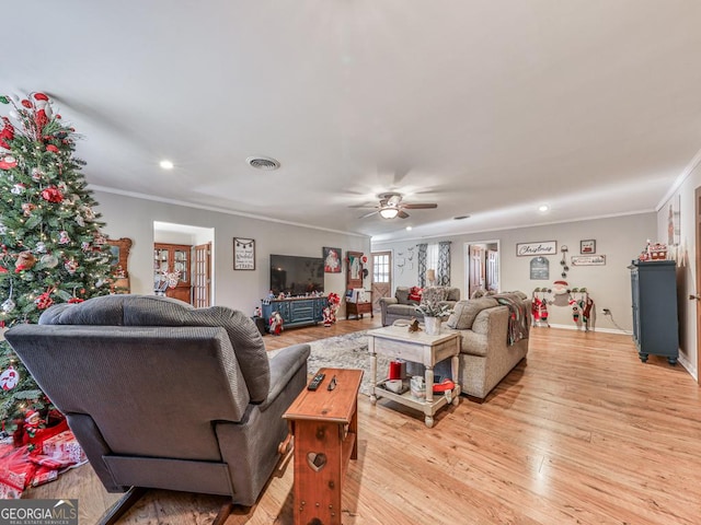 living room featuring light wood-type flooring, ceiling fan, and crown molding