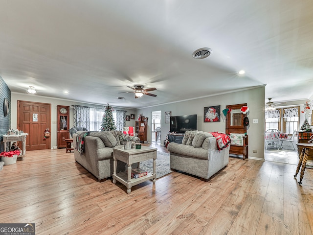 living room featuring a wealth of natural light, light hardwood / wood-style flooring, and crown molding