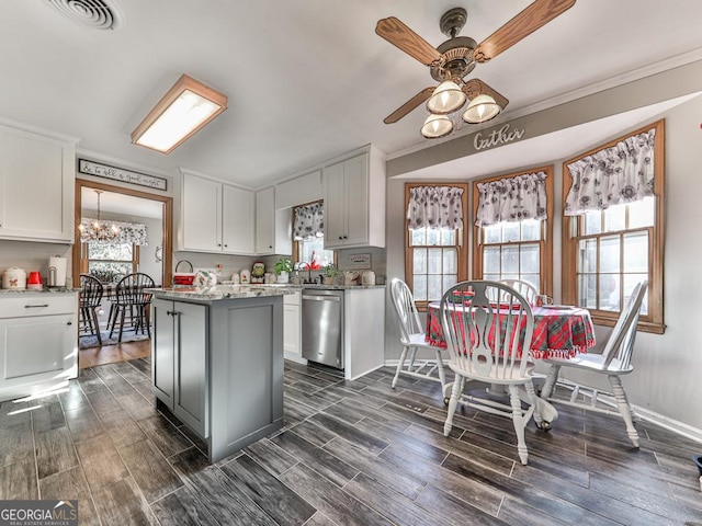 kitchen featuring white cabinetry, dishwasher, a center island, light stone countertops, and ceiling fan with notable chandelier