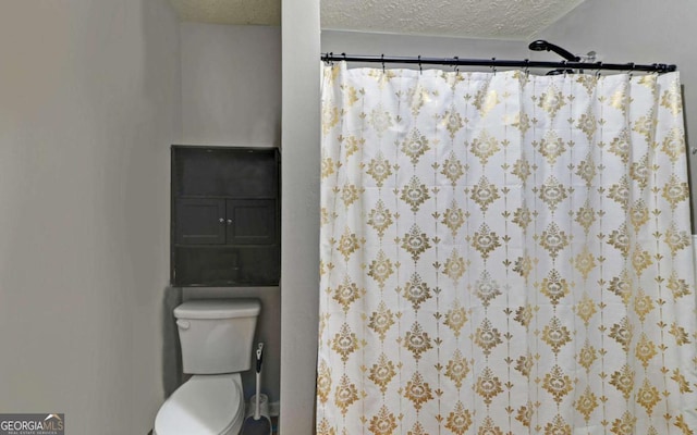 bathroom with a shower with shower curtain, a textured ceiling, and toilet