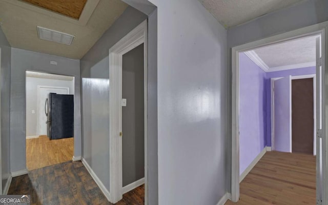 corridor featuring a textured ceiling, crown molding, and dark wood-type flooring