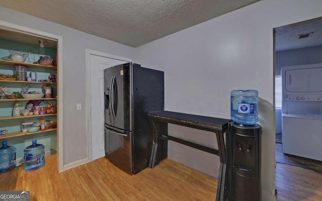 interior space with stacked washer and dryer, a textured ceiling, and hardwood / wood-style flooring