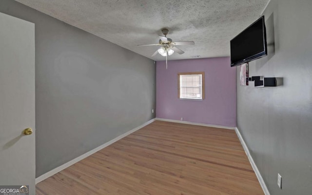 spare room featuring hardwood / wood-style floors, ceiling fan, and a textured ceiling