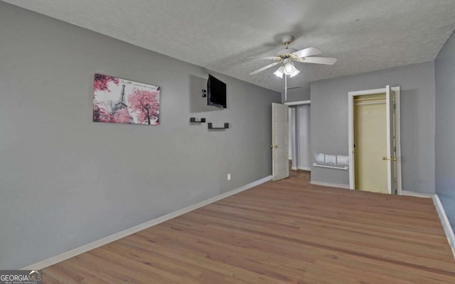 unfurnished bedroom featuring ceiling fan, a closet, light hardwood / wood-style floors, and a textured ceiling