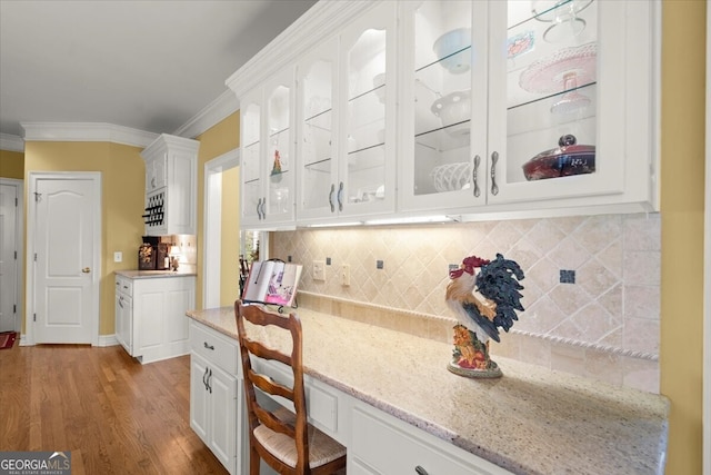 kitchen featuring white cabinets, light hardwood / wood-style flooring, light stone countertops, and crown molding