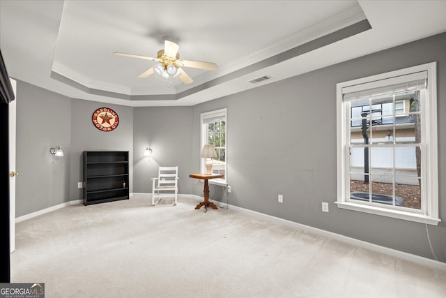 unfurnished room with a raised ceiling, crown molding, and light colored carpet