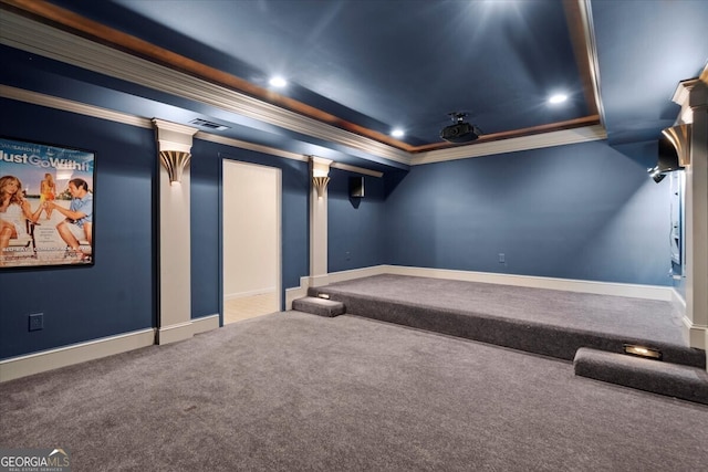 home theater room featuring carpet, ornate columns, ornamental molding, and a tray ceiling