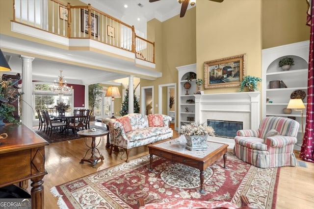 living room featuring ceiling fan with notable chandelier, hardwood / wood-style floors, and a towering ceiling