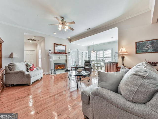 living room featuring ceiling fan with notable chandelier, light hardwood / wood-style floors, and crown molding