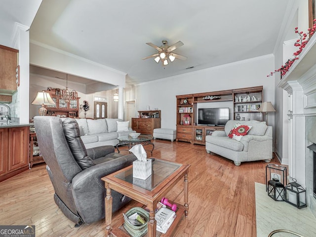 living room featuring light wood-type flooring, decorative columns, ceiling fan, and crown molding