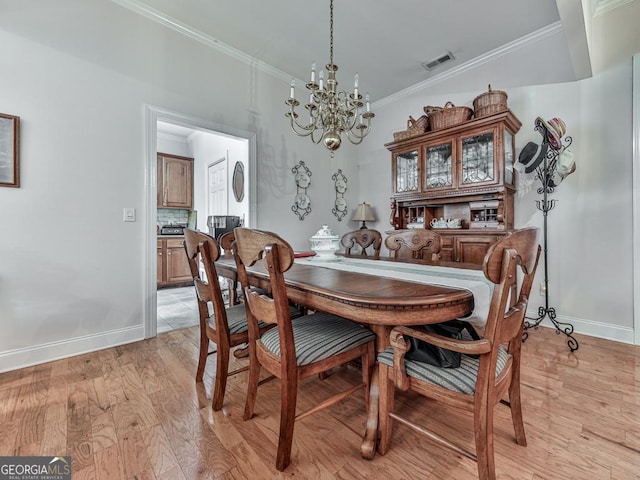 dining room with ornamental molding, light hardwood / wood-style flooring, and a chandelier